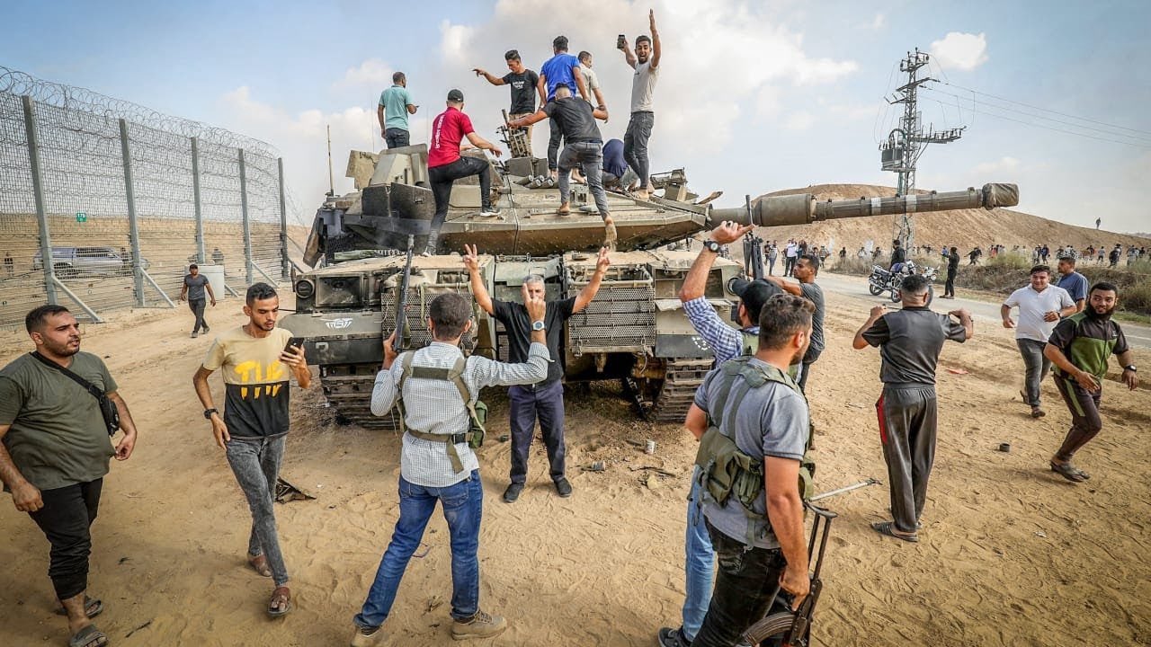 Bewaffnete Männer umzingeln einen beschädigten israelischen Panzer nach einem Grenzüberfall am 7. Oktober.