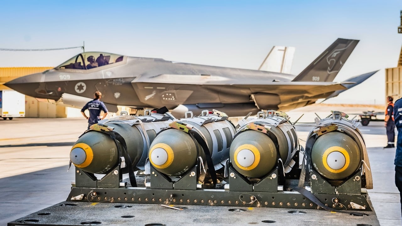 Israels Schlag gegen den Iran - F-35 Operation legt IRGC-Strukturen lahm 2 Mehrere präzisionsgelenkte Bomben auf einem Munitionswagen im Vordergrund, dahinter eine israelische F‑35I „Adir“ mit geöffnetem Cockpit auf einem Militärflugplatz.